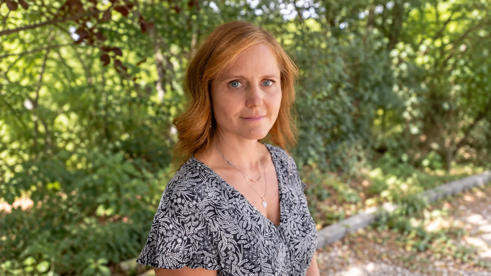 Dr. Baji Zsófia portréja zöld, fás háttér előtt.