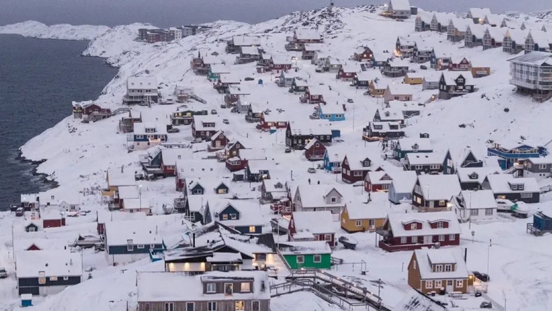Hóval borított grönlandi település színes házakkal és tengerparttal az Északi-sarkvidéken.